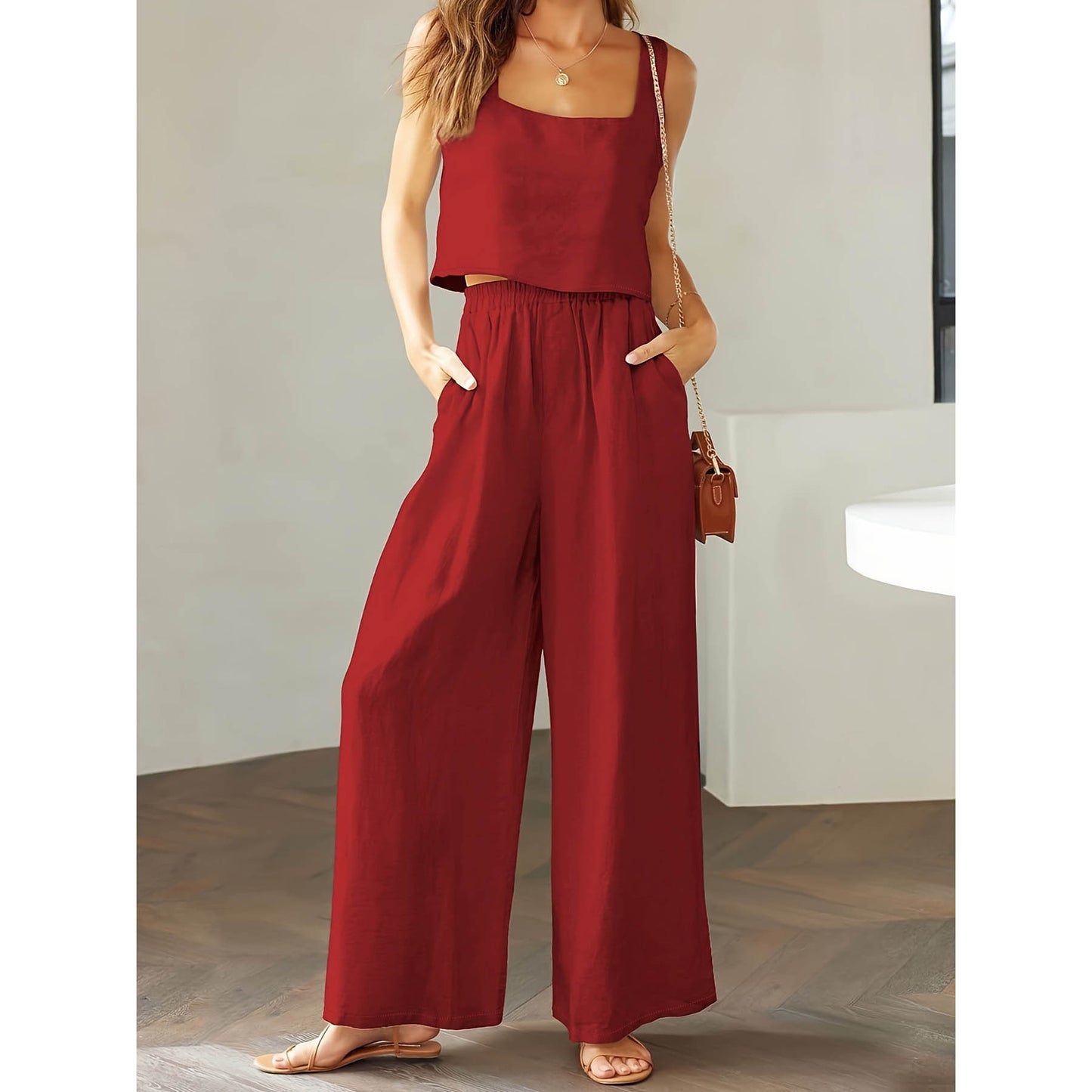 Woman wearing a red jumpsuit standing indoors with a neutral background