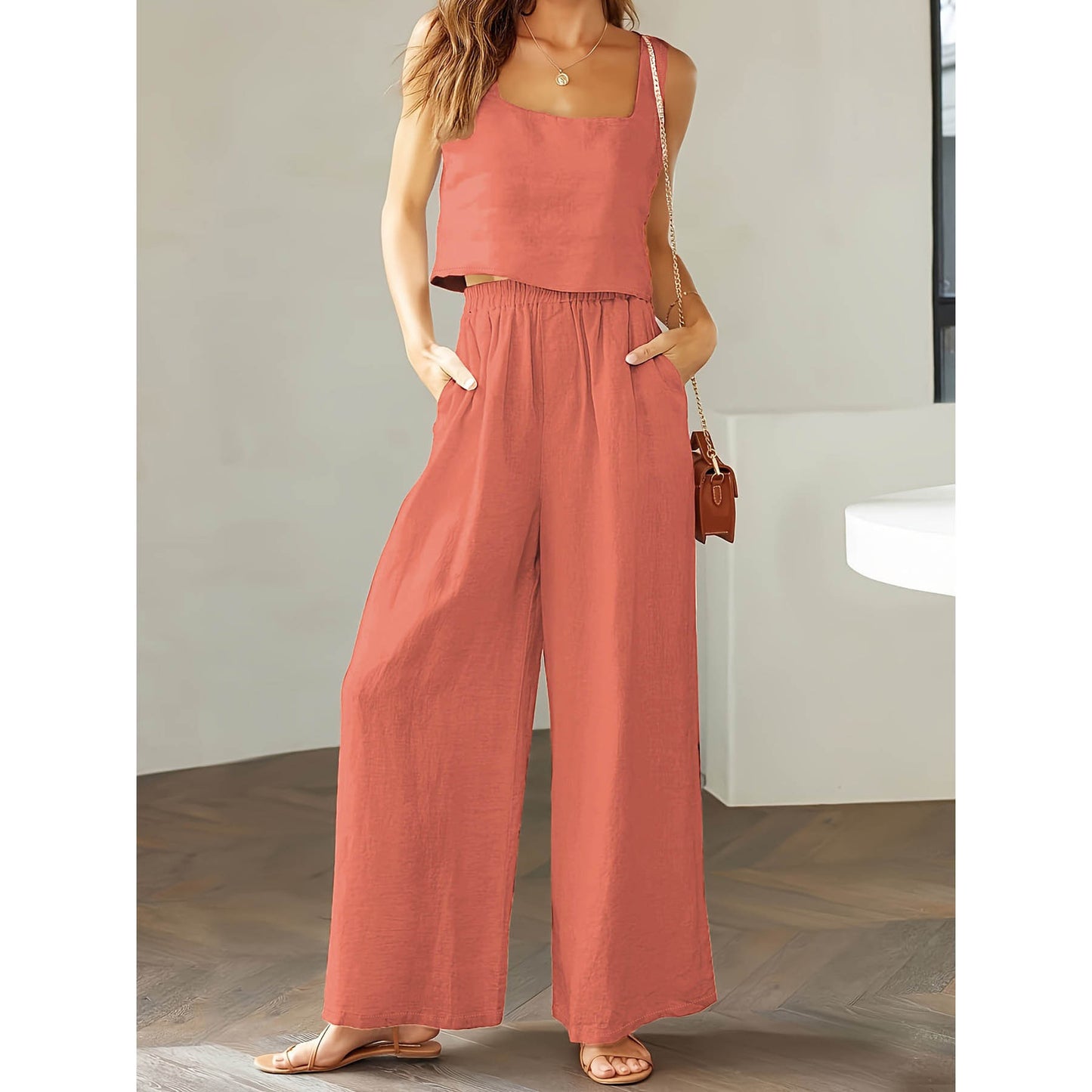 Woman wearing a pink jumpsuit standing indoors with a neutral background