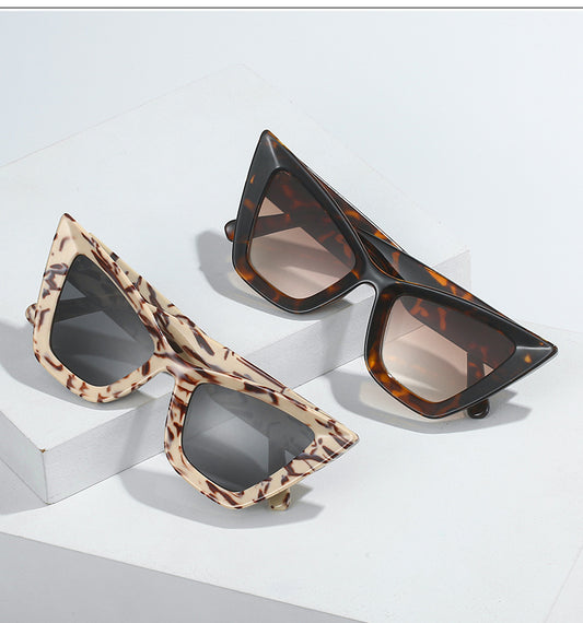Two pairs of cat-eye sunglasses with tortoiseshell and brown frames on a light gray background.