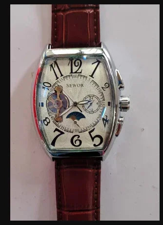 Tonneau watch with maroon-brown leather strap, light dial, Roman numerals, and subdial ring.