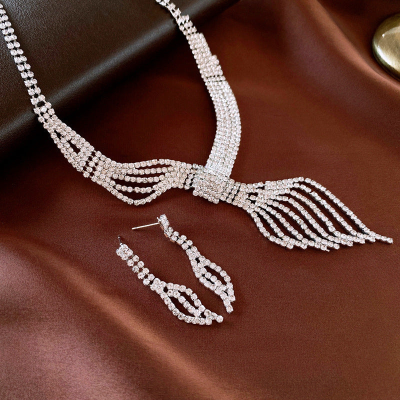 Silver necklace and earrings on a brown fabric background