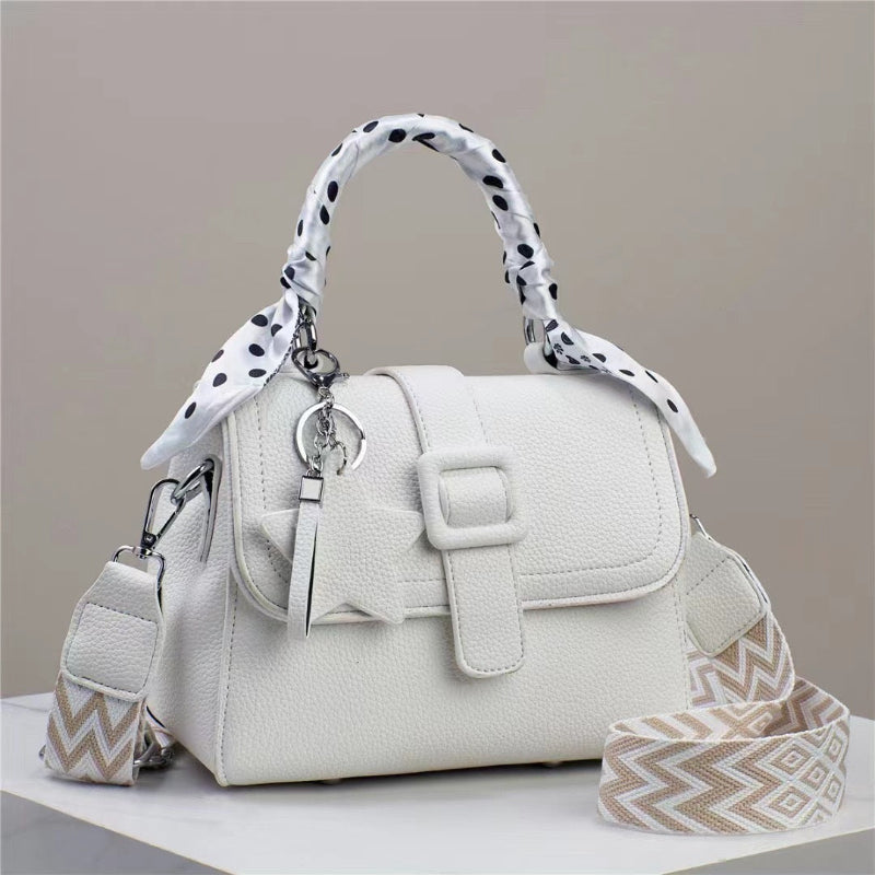 White handbag with patterned strap on a neutral background
