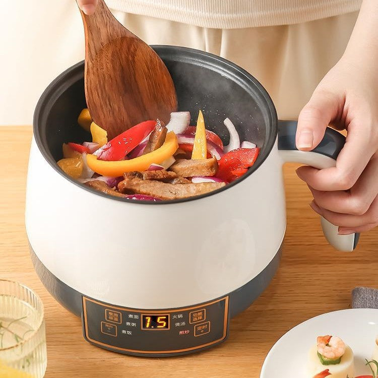 Person using a wooden spoon to stir vegetables and meat in a white electric pot on a wooden table.