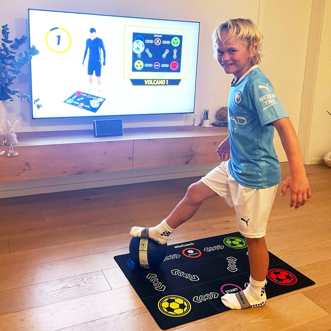 Training mat with soccer ball icons; child practices footwork indoors