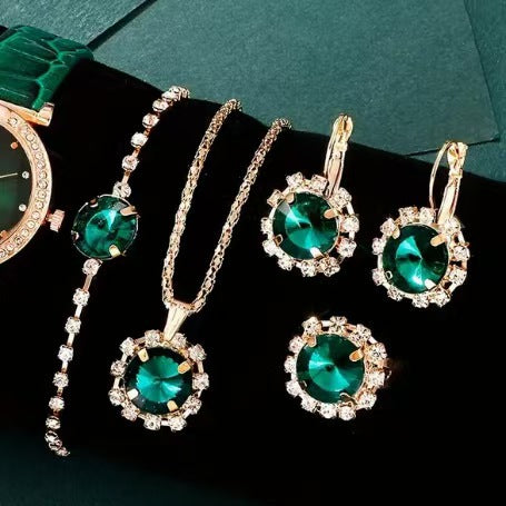 Jewelry set with green gemstones on a dark surface