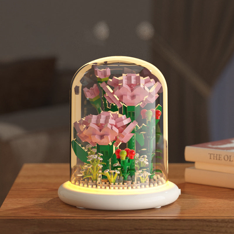 Decorative night light with pink flowers and green leaves on a wooden surface.