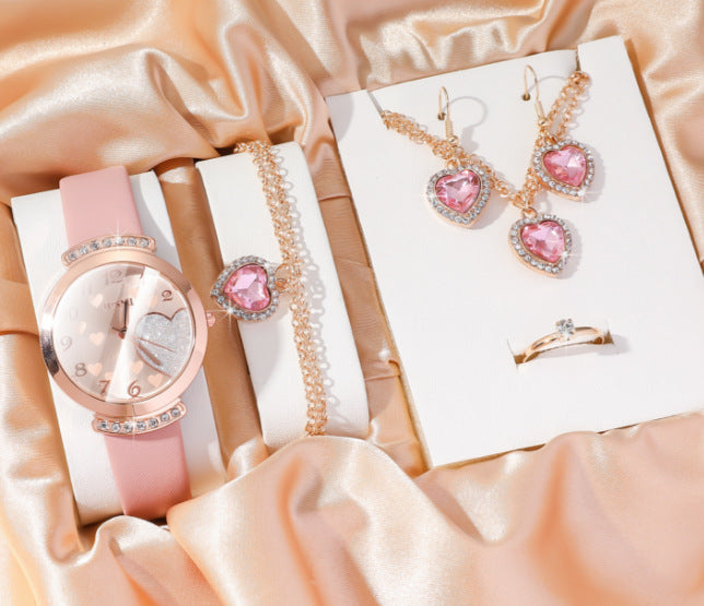 Jewelry set including a watch, bracelet, and earrings on a satin surface