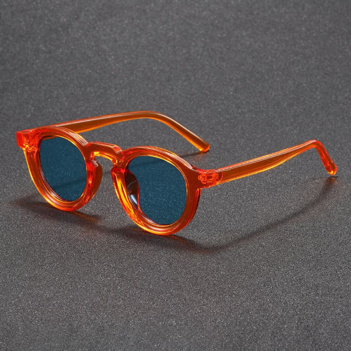 Round sunglasses with orange frame and blue lenses on a gray background