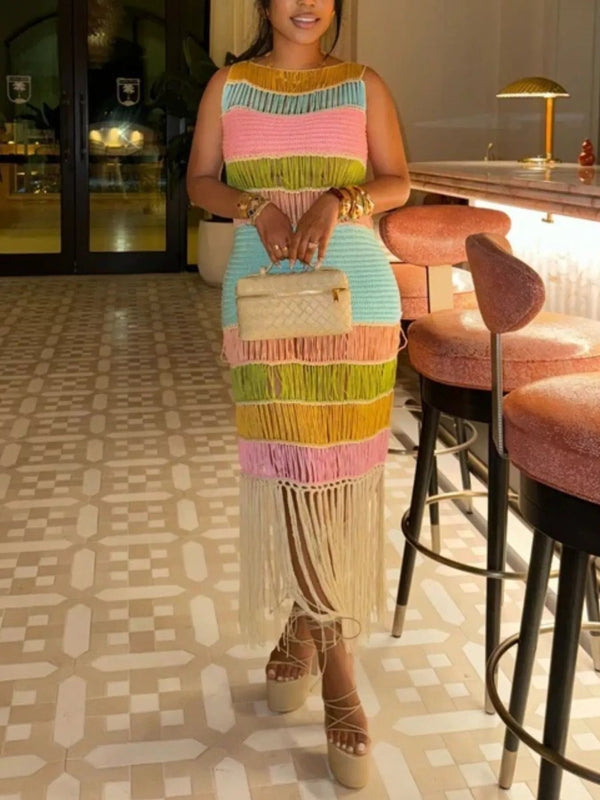 Woman in a colorful dress with fringe holding a handbag in an indoor setting.