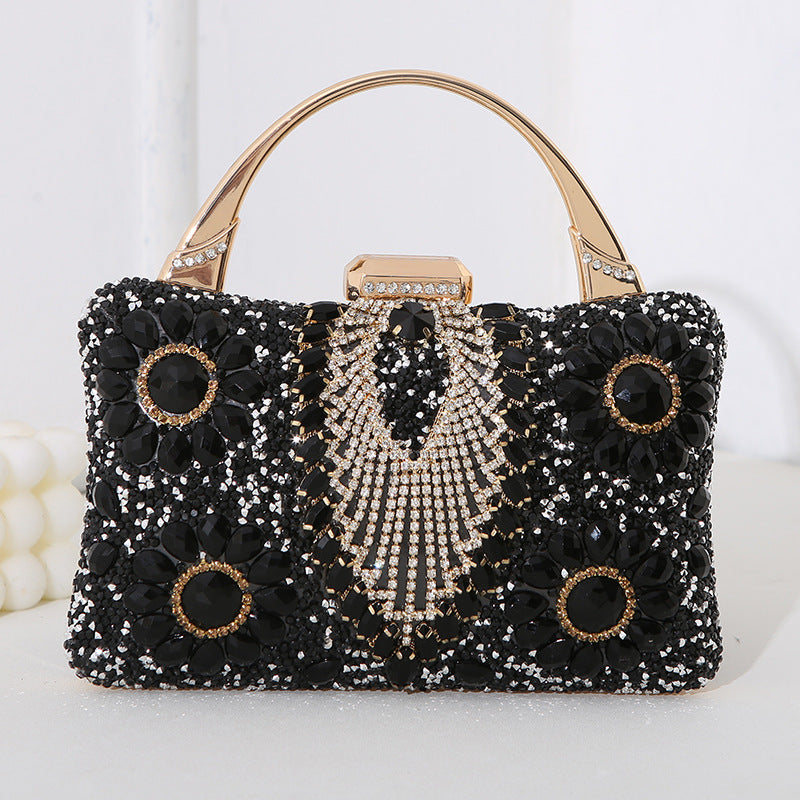 Black handbag with floral and shell designs on a white background