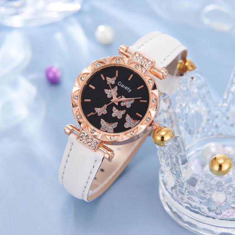Rose gold watch with butterfly design on a white strap against a light blue background