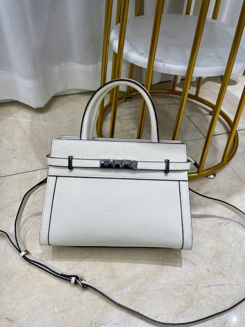White handbag with a black strap on a marble floor