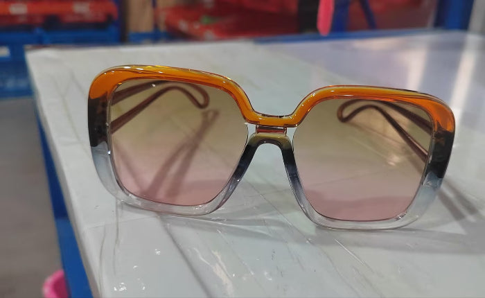 Sunglasses with orange and pink gradient lenses on a white surface