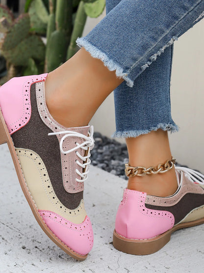 Pink, tan, and dark color-block lace-up flats with white laces and round toe