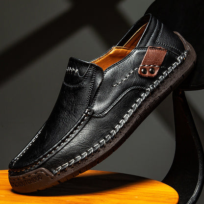 Black leather loafer shoe on a wooden surface with a dark background