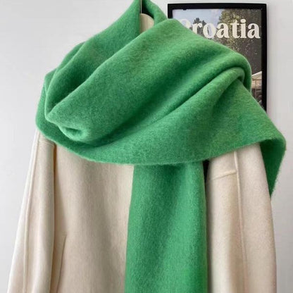 Green scarf draped over a white surface with a blurred background