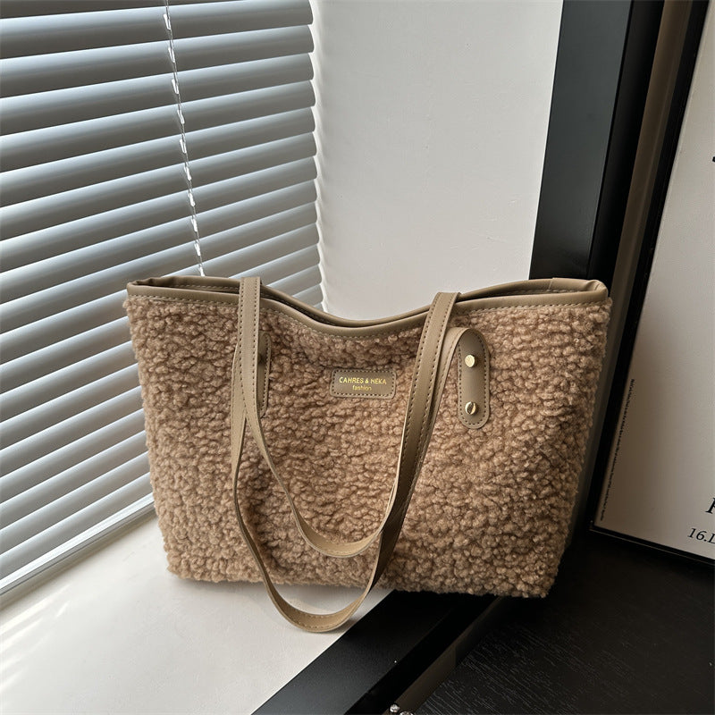 Light tan furry tote shoulder bag with dual handles and front logo patch