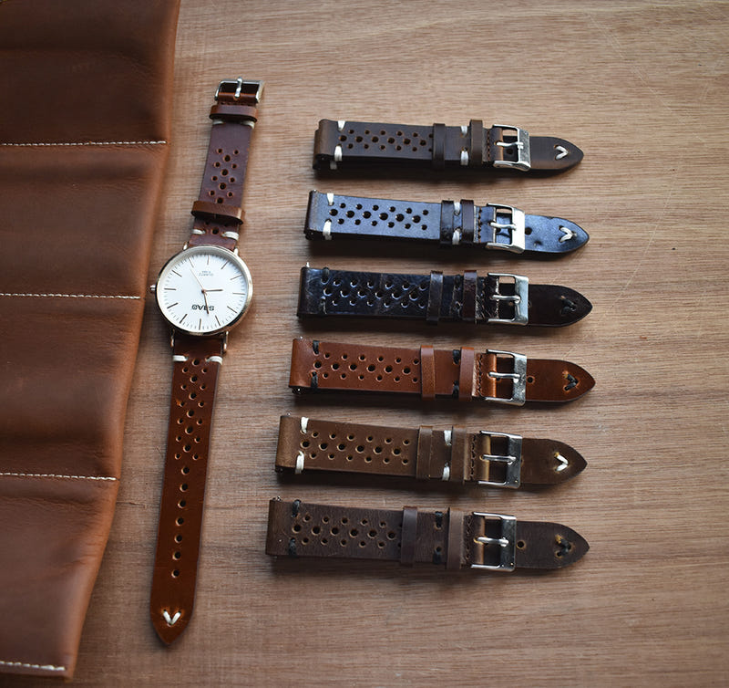 Multiple leather watch straps with punched holes and metal buckles in brown and dark tones