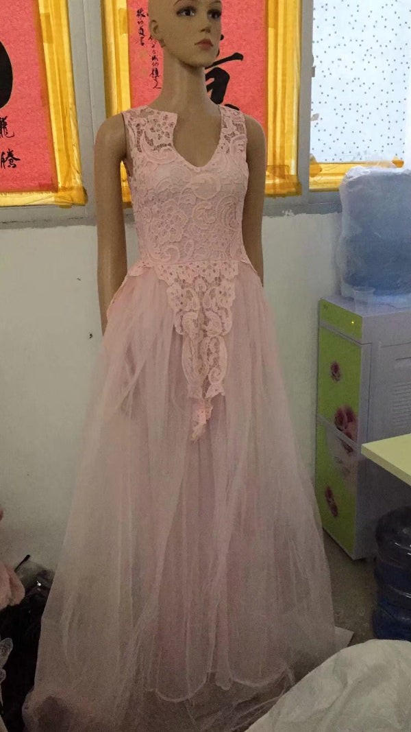 Mannequin wearing a pink lace dress in an indoor setting with posters on the wall.