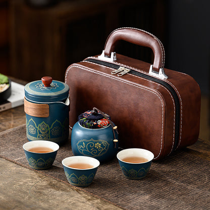 Tea set with blue teacups and a brown leather suitcase on a wooden surface.