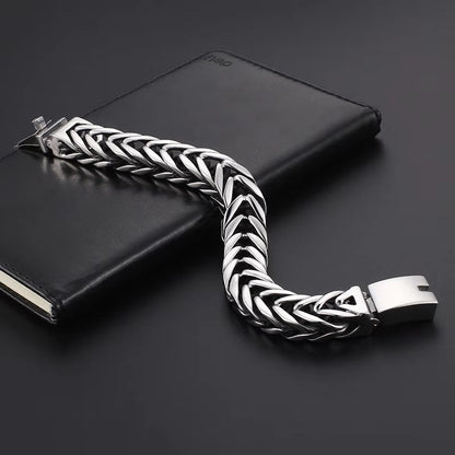 Silver braided bracelet on a black surface with a black notebook