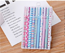 Set of colorful pens in a clear case on a wooden surface with a letter.