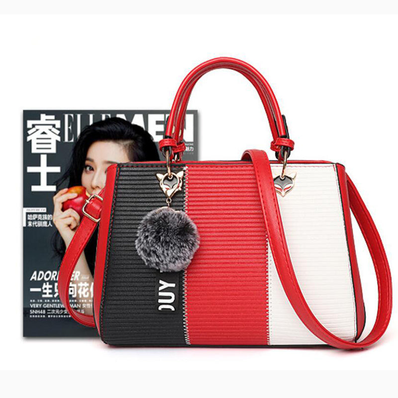 Multicolored handbag with a gray pom-pom charm on a white background