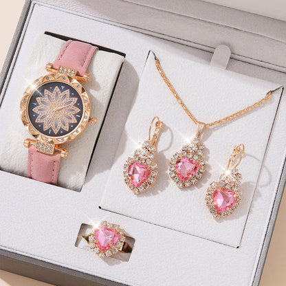 Jewelry set with pink gemstones including a watch, necklace, and earrings on a white box.