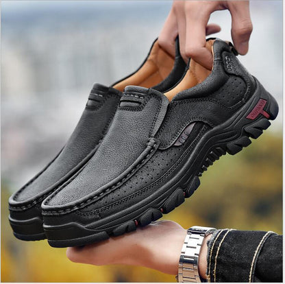 Black leather shoes held by a person with a blurred outdoor background