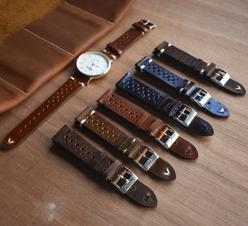 Assorted leather watch straps with perforations and metal buckles, laid on a mat