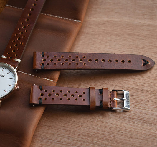 Brown perforated leather watch strap with metal buckle and keeper, arched end