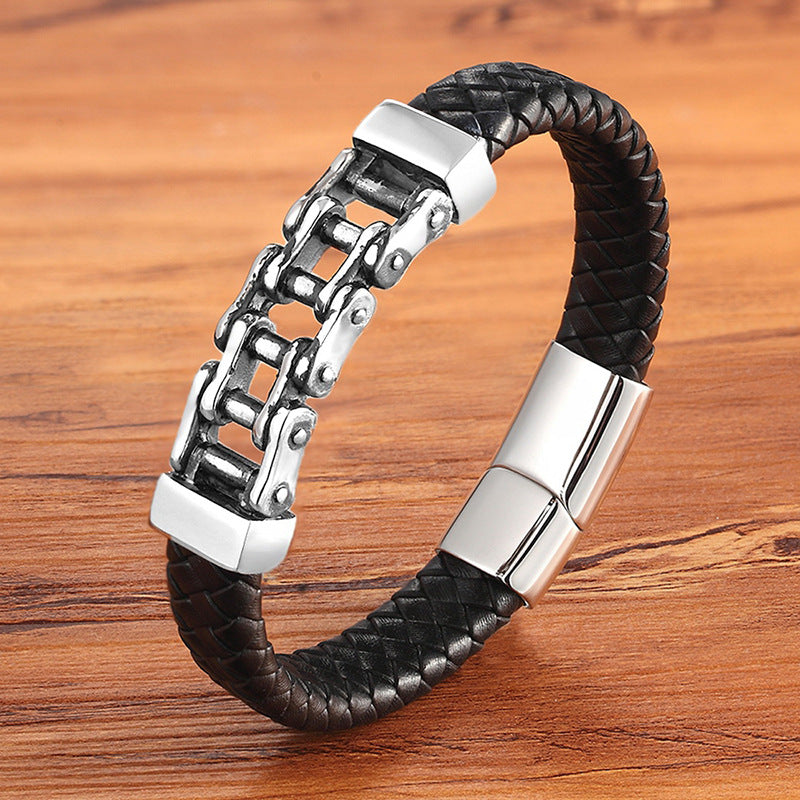 Black braided leather bracelet with silver metal clasp on a wooden surface