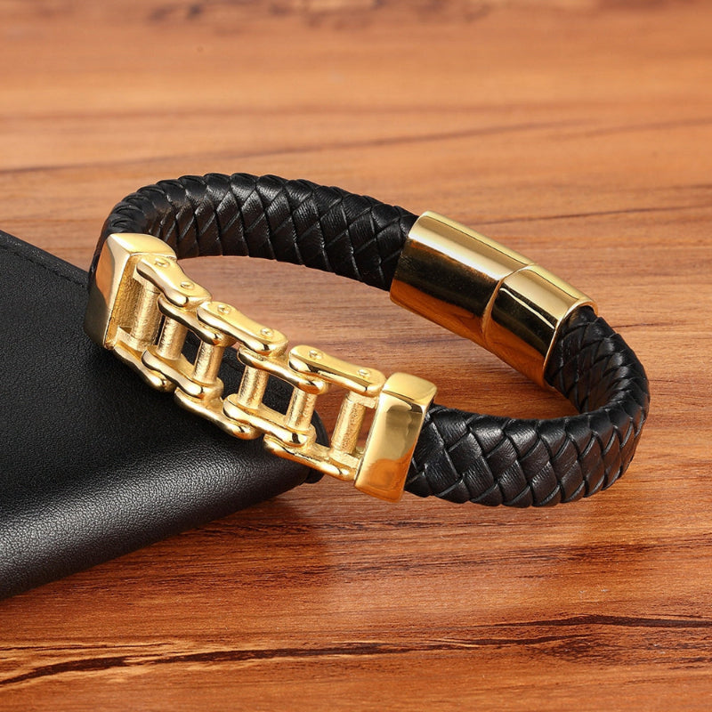 Black braided leather bracelet with gold clasp on a wooden surface