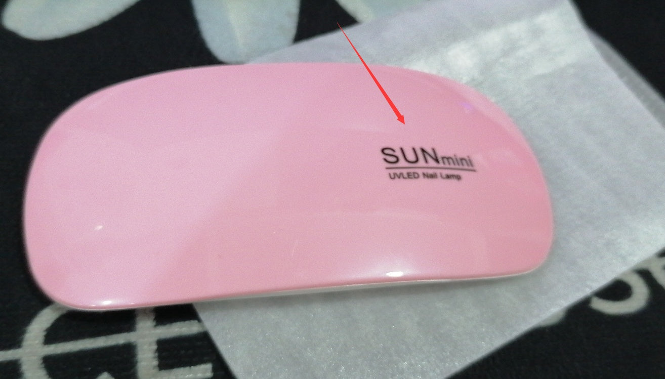 Pink UV/LED nail lamp with 'SUN mini' branding on a white surface.