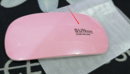 Pink UV/LED nail lamp with 'SUN mini' branding on a white surface.