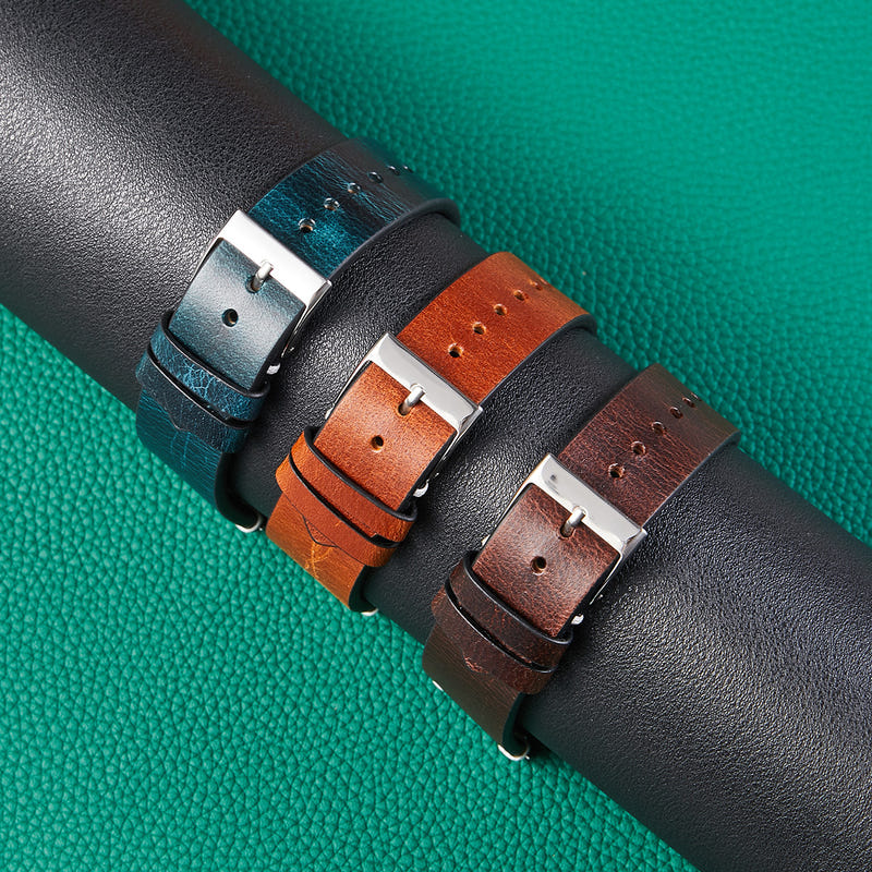 Overlapping leather watch straps with silver buckles in teal, orange, and black