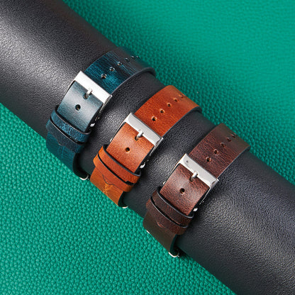 Overlapping leather watch straps with silver buckles in teal, orange, and black
