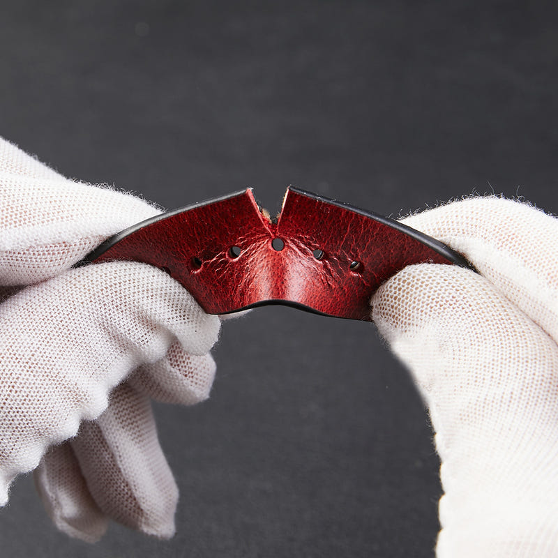 Wine red leather strap close-up with stitching, rivets, and adjustment holes