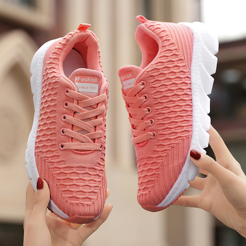 Pink sneakers held by a person with a blurred background