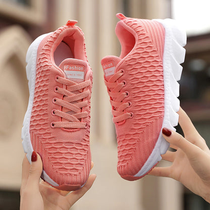Pink sneakers held by a person with a blurred background