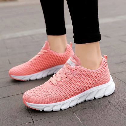 Pink sneakers with white soles worn on a pavement surface
