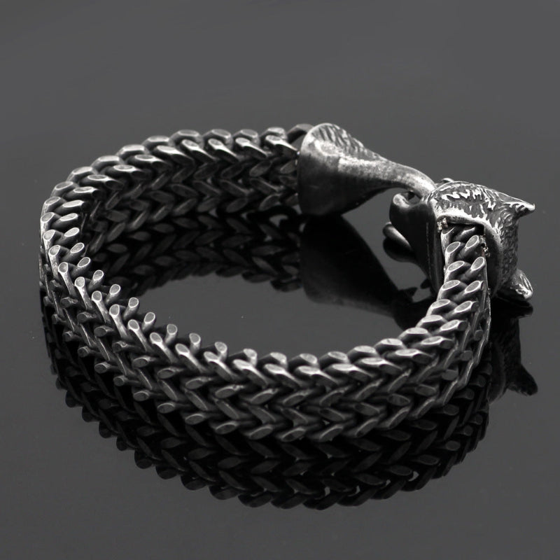 Black braided leather bracelet with a metal clasp on a dark background
