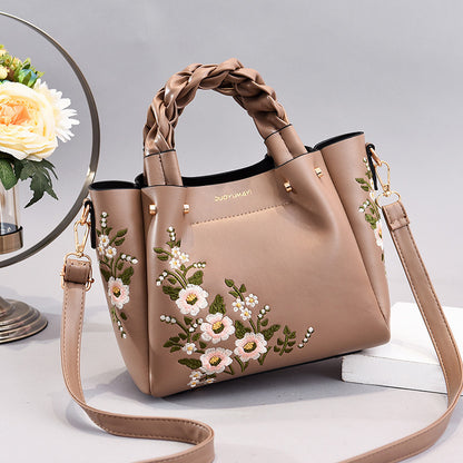 Beige handbag with floral embroidery on a light background