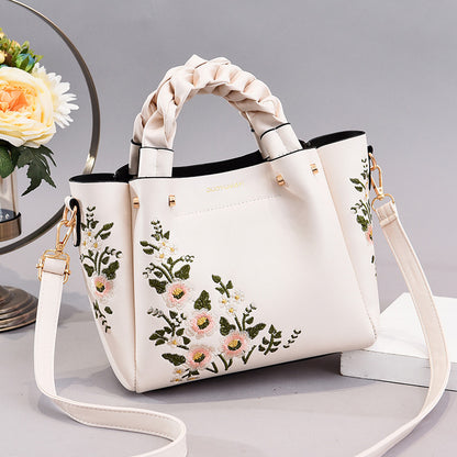White handbag with floral embroidery on a light gray background