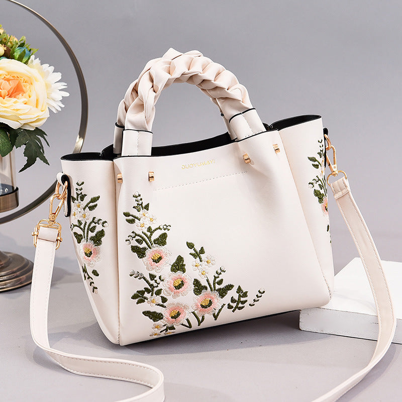 White handbag with floral embroidery on a light gray background