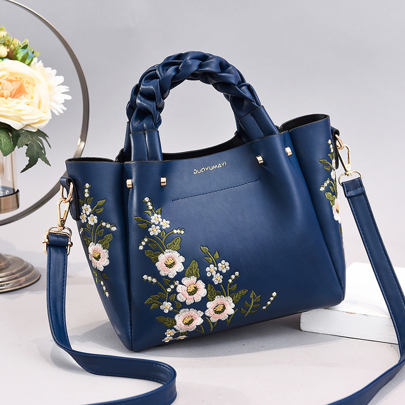 Blue handbag with floral embroidery on a light background