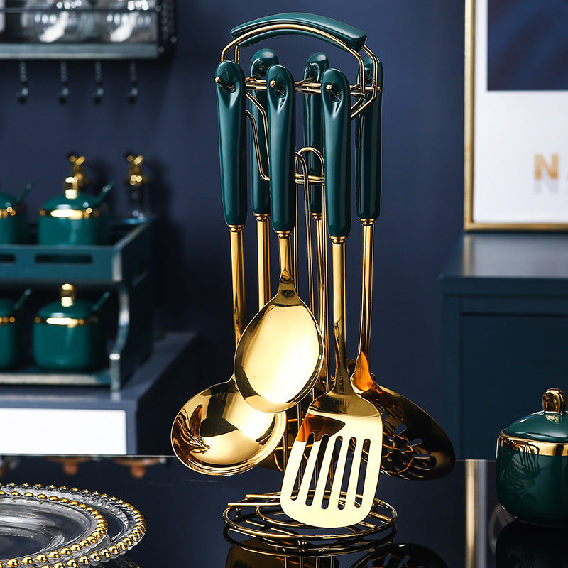Set of gold and green kitchen utensils on a dark surface with a blurred background