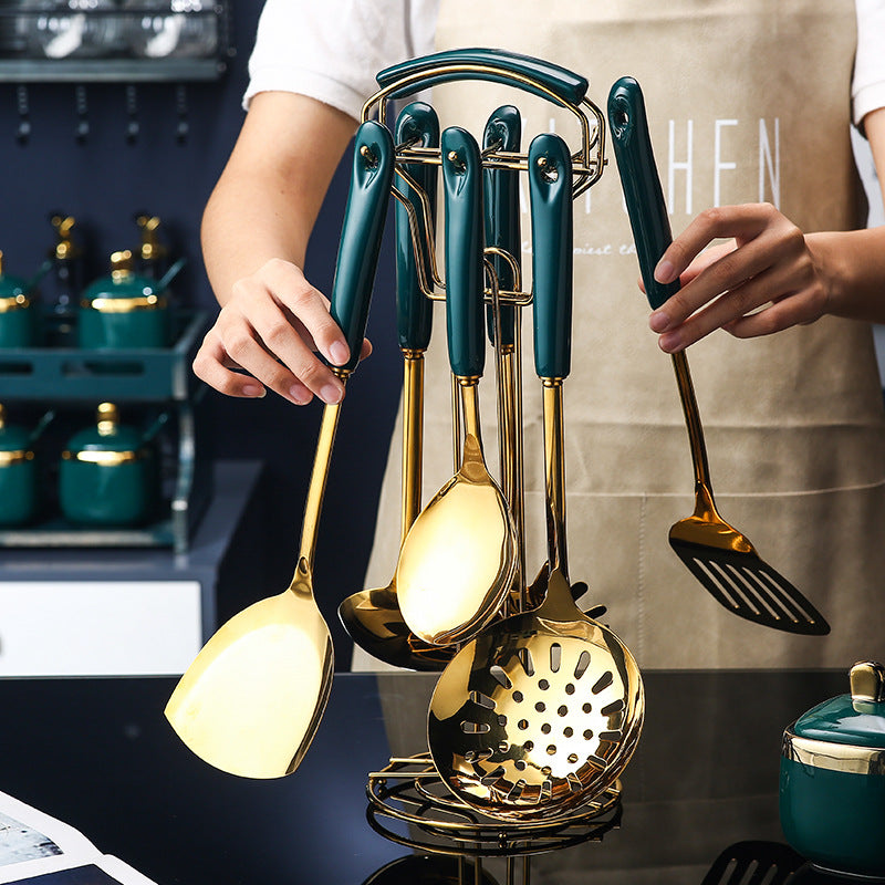 Set of gold and green kitchen utensils on a stand with a person holding them.