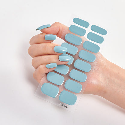 Hand holding a sheet of light blue nail stickers against a white background