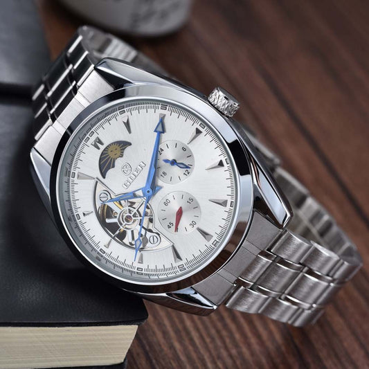 Silver wristwatch with a detailed face on a wooden surface